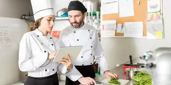 Two chefs preparing food in the kitchen